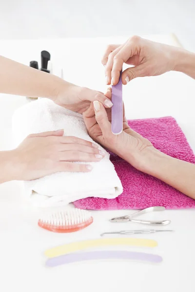 Mujer en un salón de uñas recibiendo una manicura por una esteticista . — Foto de Stock