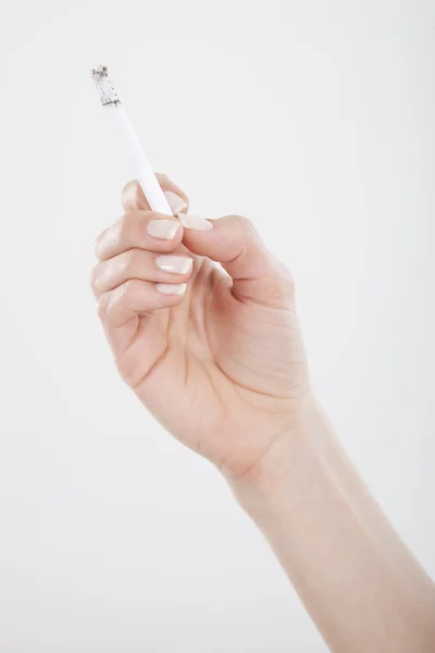 La main de la femme tient la cigarette sur fond blanc . — Photo
