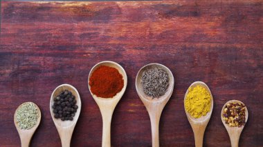 Tahta kaşıklar aromatik otlar ve baharatlar ahşap kesme tahtası üzerinde dolu