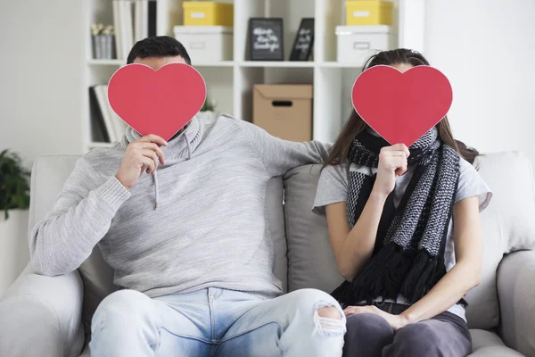 Пара прячет лица за бумажными сердцами — стоковое фото