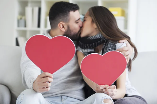 Casal beijando atrás de corações de papel — Fotografia de Stock