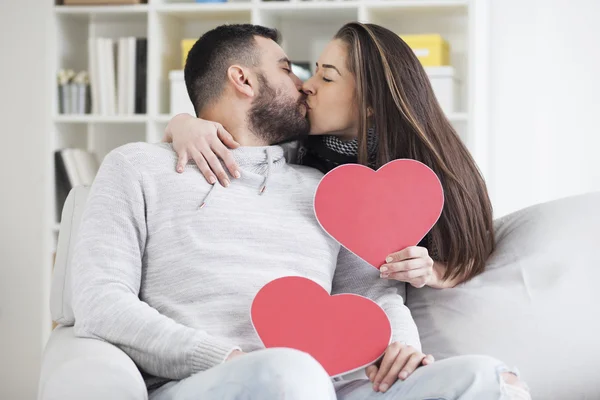 Casal beijando atrás de corações de papel — Fotografia de Stock