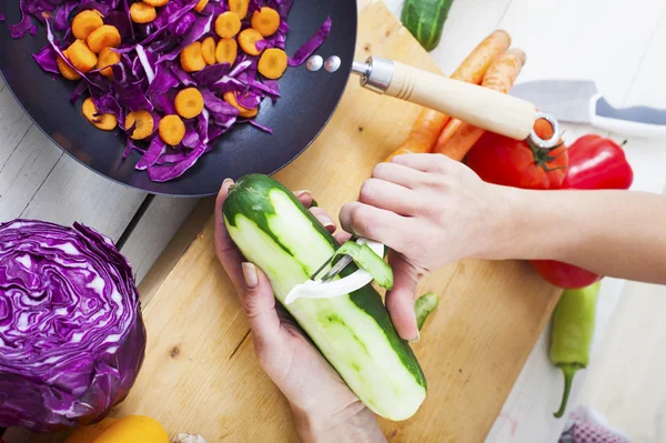Azok a handek, peeling uborka. Felkészülés saláta vagy wok. Egészséges zöldség — Stock Fotó