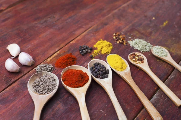 Tahta kaşıklar aromatik otlar ve baharatlar ahşap kesme tahtası üzerinde dolu