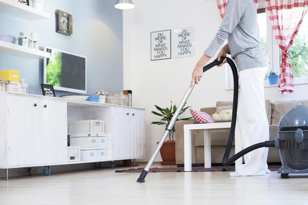 Close up of woman with legs vacuum cleaner cleaning floor at home — Stock Photo, Image