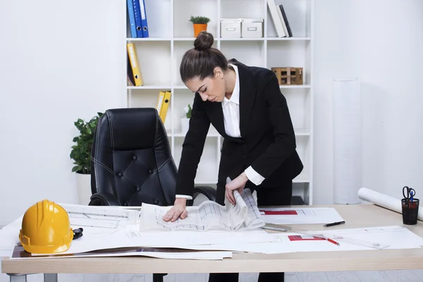 Female architect studying plans in office