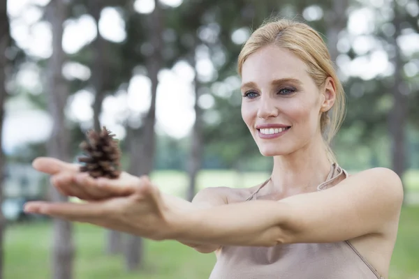Young beautiful happy woman in park holds pinecone, summer outdoors — Stock Photo, Image