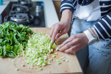 Mutfakta yemek pişiren kadın. Etrafında malzemelerle.