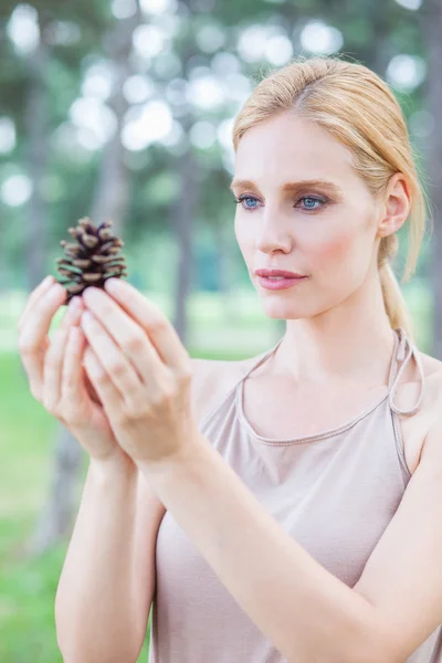 Mulher no parque segurando pinecone — Fotografia de Stock