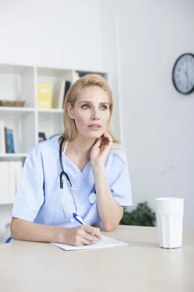 Médico feminino sentado na mesa de escritório trabalhando — Fotografia de Stock