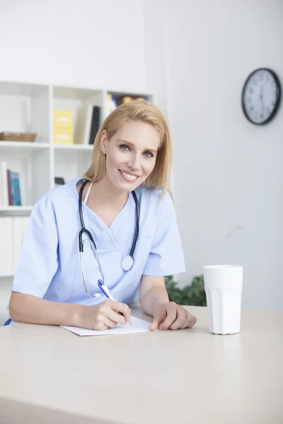 Dokter wanita duduk di meja kantor bekerja — Stok Foto