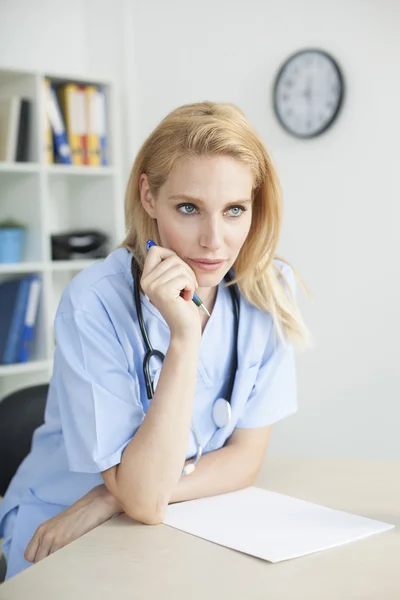 Young female doctor and practitioner working at desk — Stock Photo, Image