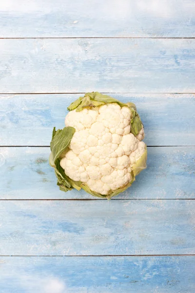 Cauliflower in hands with wooden board — Stock Photo, Image