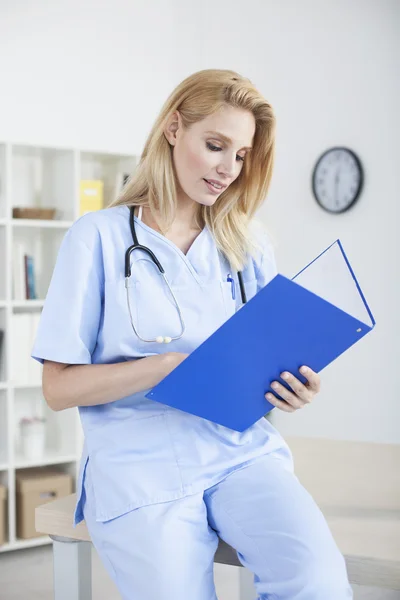 Joven hermosa doctora y practicante trabajando en el escritorio — Foto de Stock