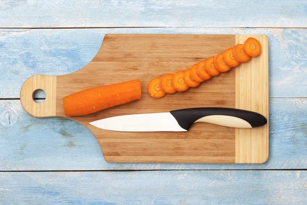 Cenouras picadas e faca em uma tábua de madeira — Fotografia de Stock