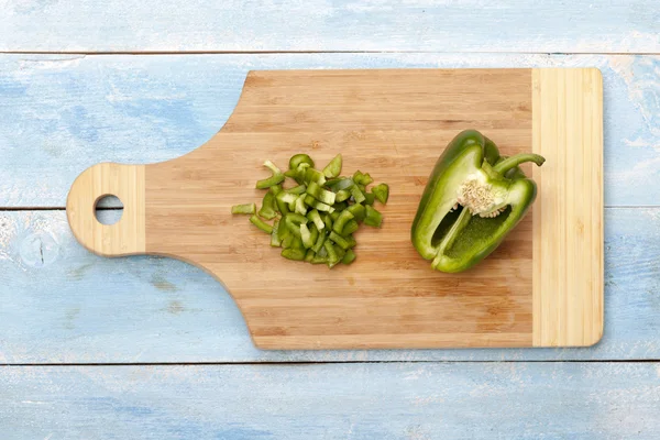 Groene peper op houten bord op blauwe tafel — Stockfoto
