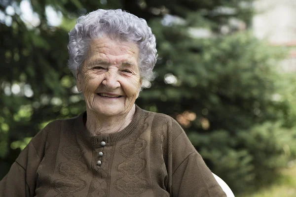 Gelukkig bejaarde vrouw zitten in de tuin — Stockfoto