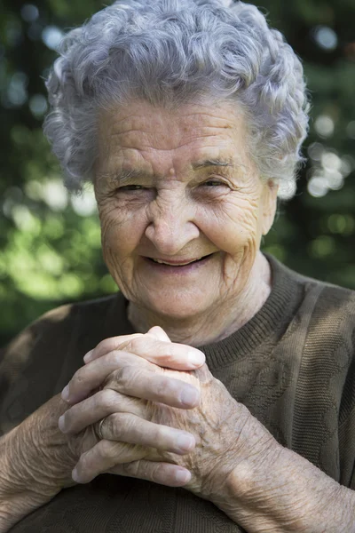 Gelukkig bejaarde vrouw zitten in de tuin — Stockfoto