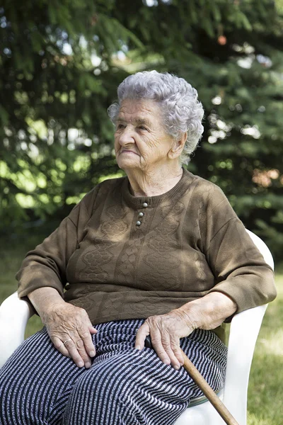 Happy elderly woman sitting in garden — Stock Photo, Image