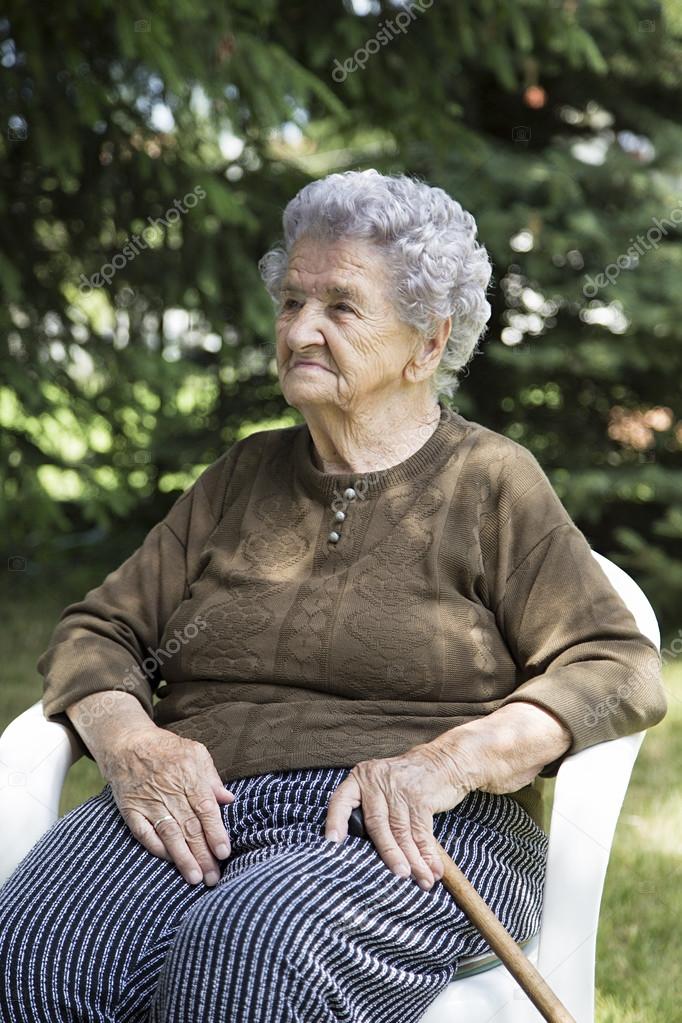 Happy elderly woman sitting in garden Stock Photo by ©Nikodash 122736254