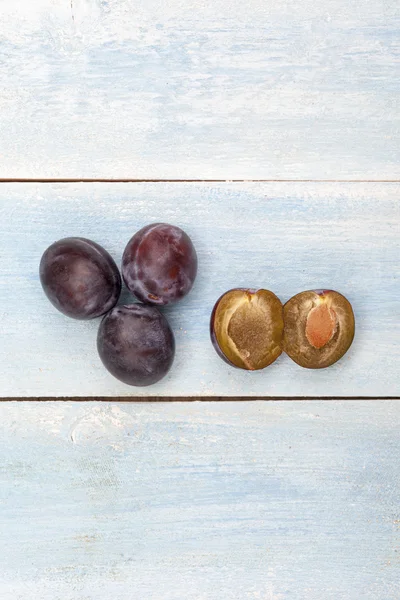 Prunes sur panneau en bois bleu, vue de dessus — Photo