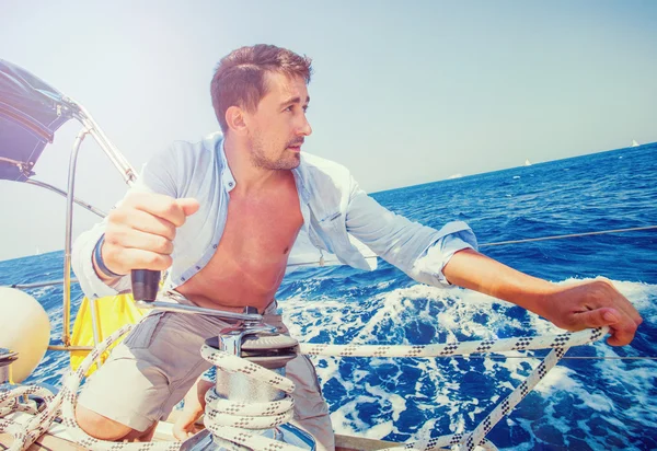 Sailing crew member pulling rope on sailboat