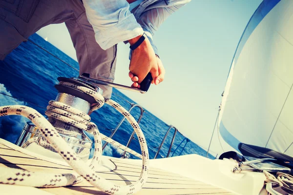 Besatzungsmitglied zieht Seil auf Segelboot — Stockfoto