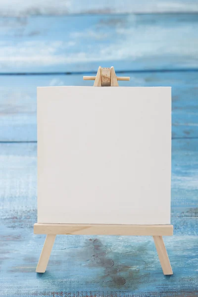 Piccolo cavalletto con foglio album di carta su tavola di legno — Foto Stock