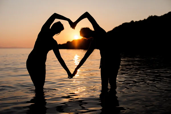 Glada vänner på stranden i havet solnedgång — Stockfoto