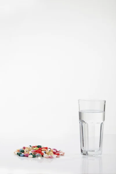 Pastillas cápsulas de medicamento con vaso de agua — Foto de Stock