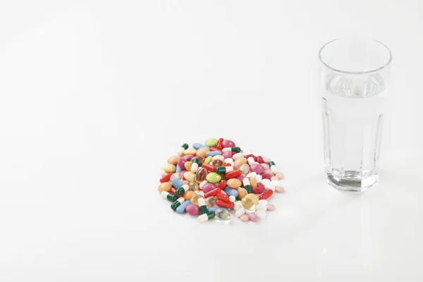 Pastillas cápsulas de medicamento con vaso de agua — Foto de Stock