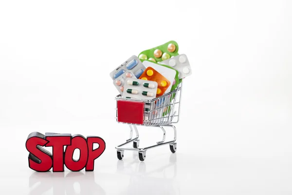 Drugs and pills in supermarket trolley with sign stop — Stock Photo, Image