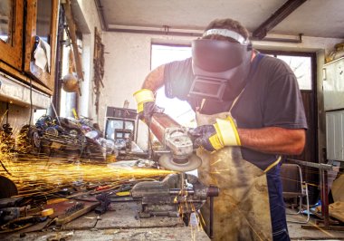 Master grinder grinds metal in workshop