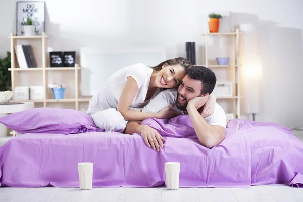 Feliz joven pareja en la cama sofá en habitación ded —  Fotos de Stock