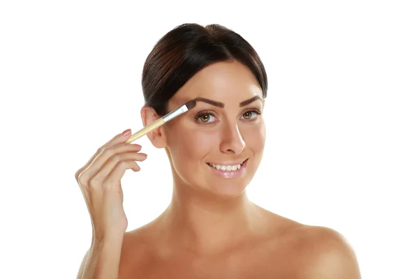 Woman holding brush and applying make-up — Stock Photo, Image