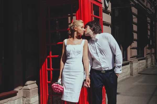 Panna młoda i pan młody całuje na tle budki telefonicznej. Turystyka, Podróże ludzi pojęcie - szczęśliwa para starszy Londyn miasto ulica w Anglii — Zdjęcie stockowe