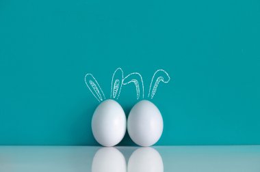 Mavi arka plan üzerinde tavşanlar gibi Paskalya yumurta boyalı