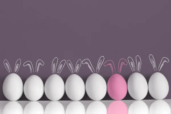 Conejo rosa entre conejos blancos como huevos de Pascua — Foto de Stock