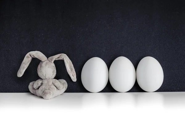 Conejo de Pascua con huevos de colores en la pizarra negra — Foto de Stock