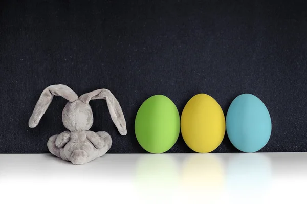 Conejo de Pascua con huevos de colores en la pizarra negra — Foto de Stock