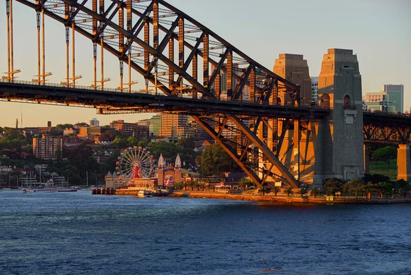 夕日はシドニー港の橋とシドニーのダーリング港の街並みに暖かい輝きを投げかけます ロイヤリティフリーのストック写真