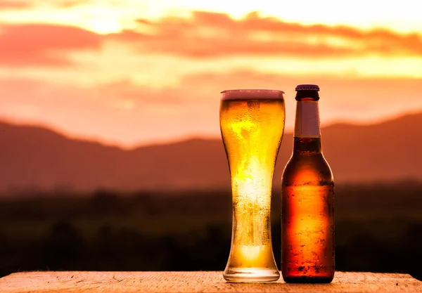 Garrafa e Copo de cerveja leve no pôr do sol — Fotografia de Stock