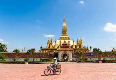 Vientiane, Laos - 25 Ekim 2014: Bisiklet wat Phra ki Luang pagoda Vientiane, Laos yakınındaki Merkezi şehir meydanında gıda satan geleneksel konik şapkalı belirsiz yerel kadın