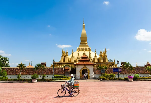 Vientiane, Laos - 25 Ekim 2014: Bisiklet wat Phra ki Luang pagoda Vientiane, Laos yakınındaki Merkezi şehir meydanında gıda satan geleneksel konik şapkalı belirsiz yerel kadın