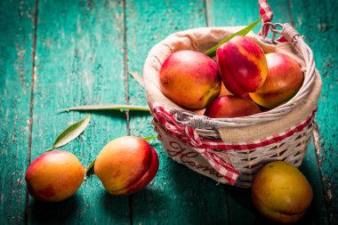 Rustik ahşap masa üzerinde bir sepet içinde taze şeftali.