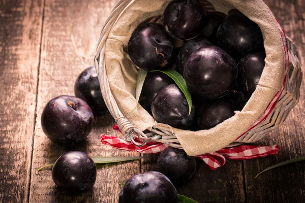 Frische Pflaumen im Korb auf rustikalem Holztisch. — Stockfoto