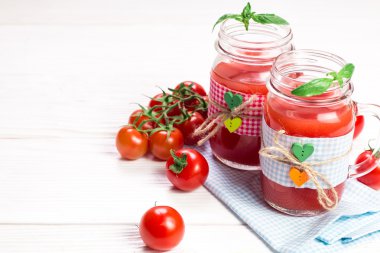 Beyaz ahşap zemin üzerinde taze domates ve domates suyu