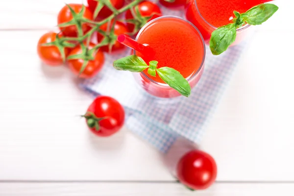 Tomatensap en verse tomaten op een witte houten achtergrond — Stockfoto