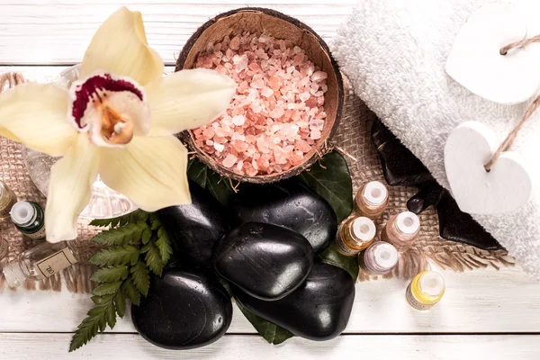 spa concept with stones, flowers , essential oils and mineral salt  on wooden table