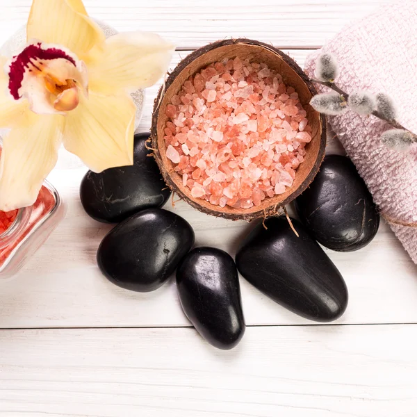 Spa konsept taşlar, çiçek, uçucu yağlar ve ahşap masa üzerinde mineral tuz 